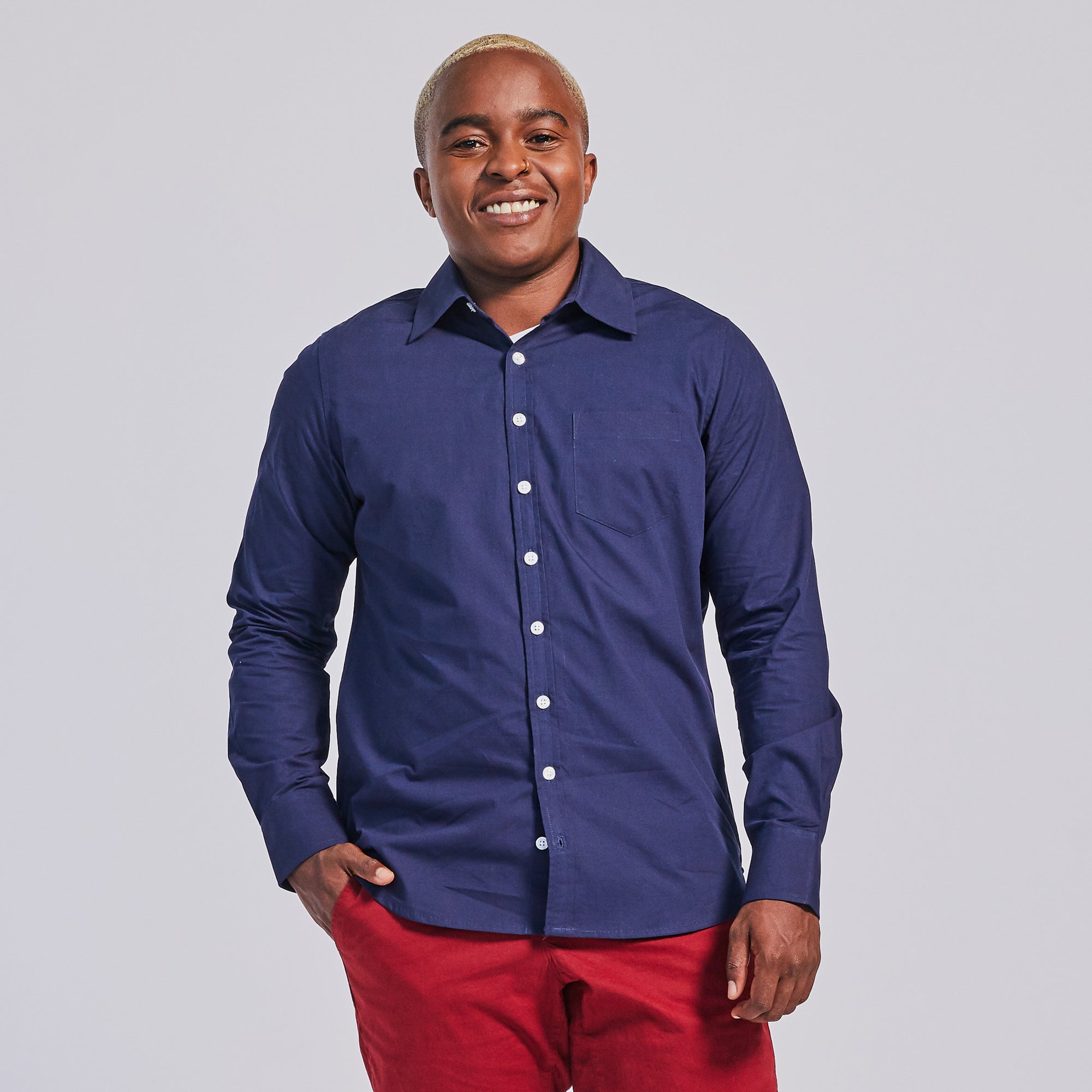 Masc presenting model in navy chambray point collar long sleeve shirt. Color: Navy