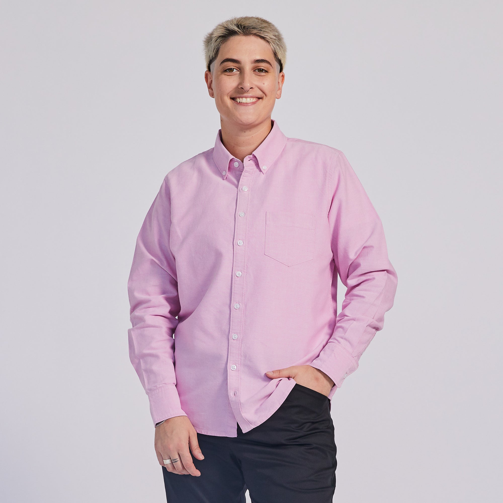 non-binary model in pink button down Oxford shirt. Color: Pink