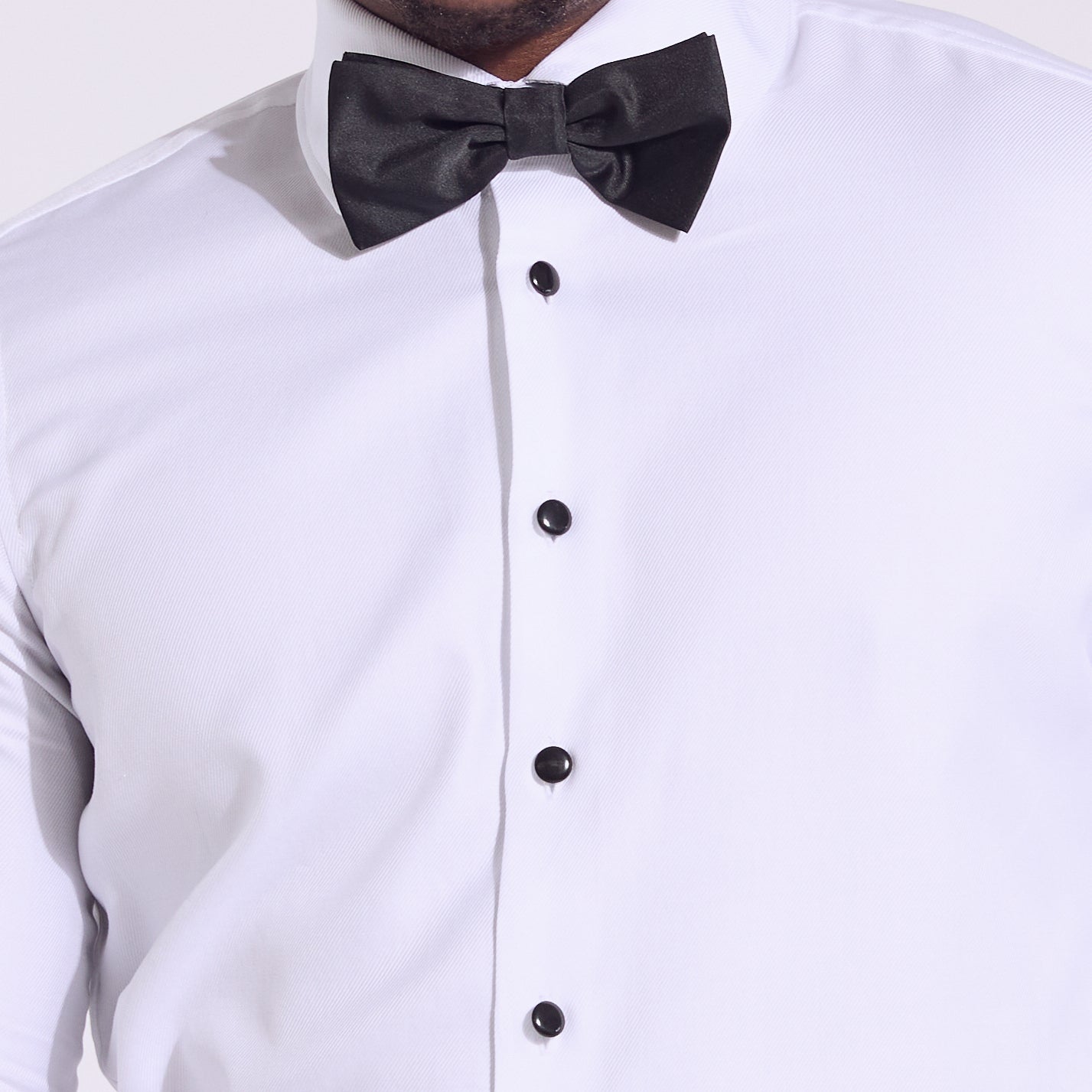 White dress shirt with black bow tie and buttons on a white background. Color: Black