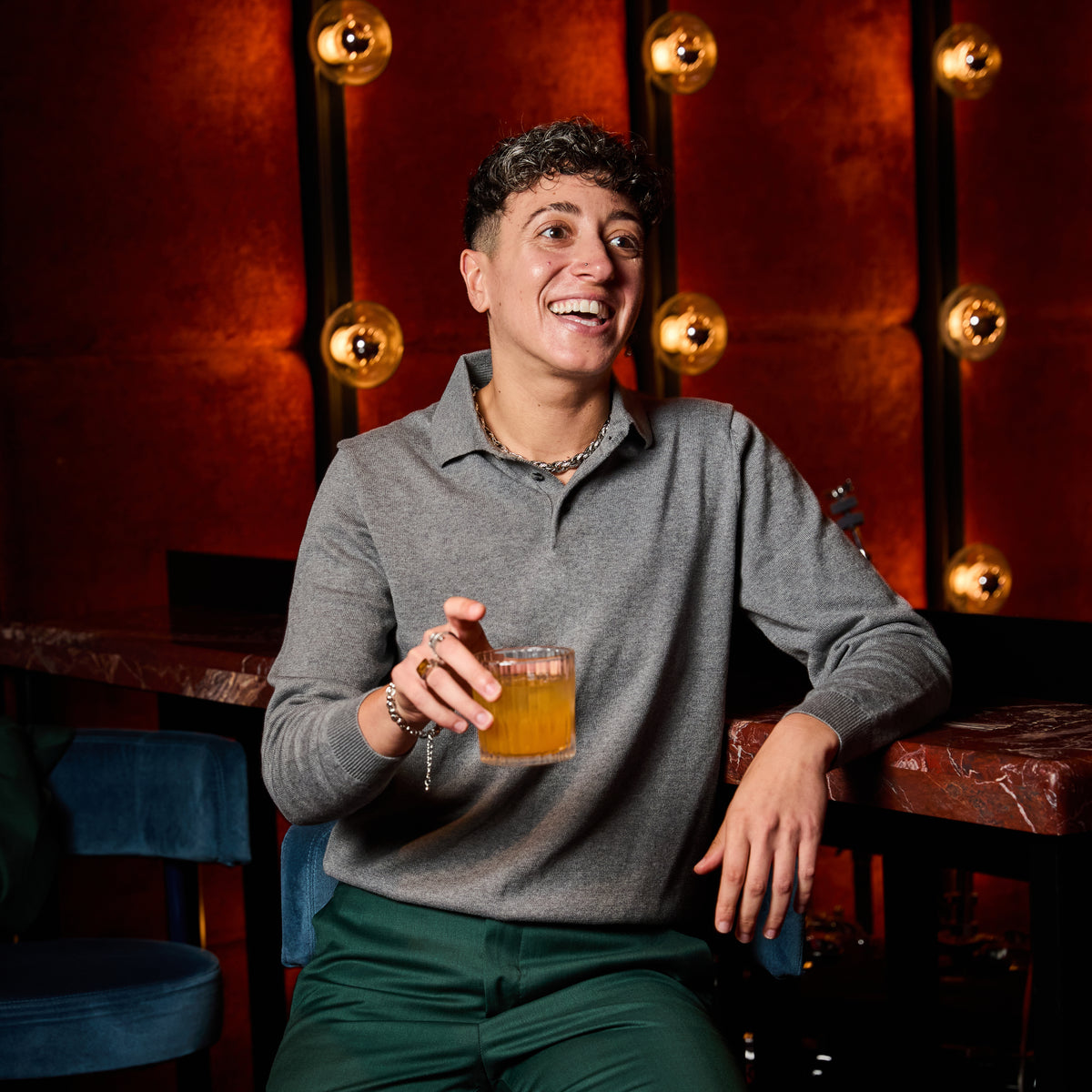 Model wearing Gray long sleeve polo sweater at a bar. Color: Gray Heather 