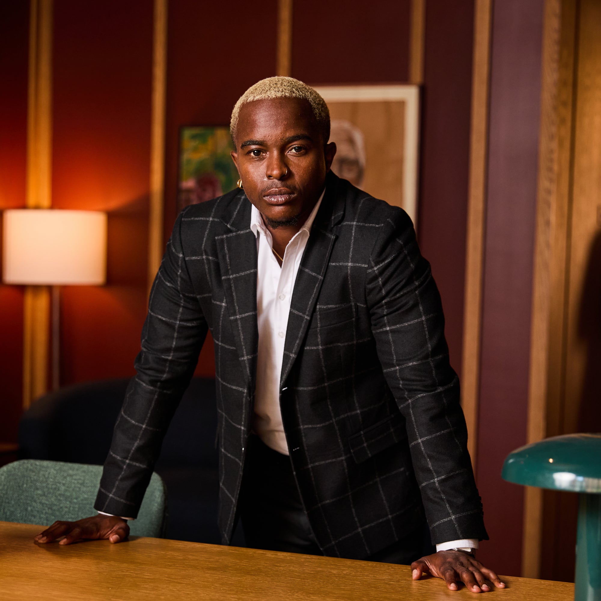 Model in Finch Windowpane blazer standing at a table in an indoor setting. Color: Black Windowpane
