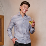 Person holding a glass of white wine against a plain background. Color: Coastal Blue
