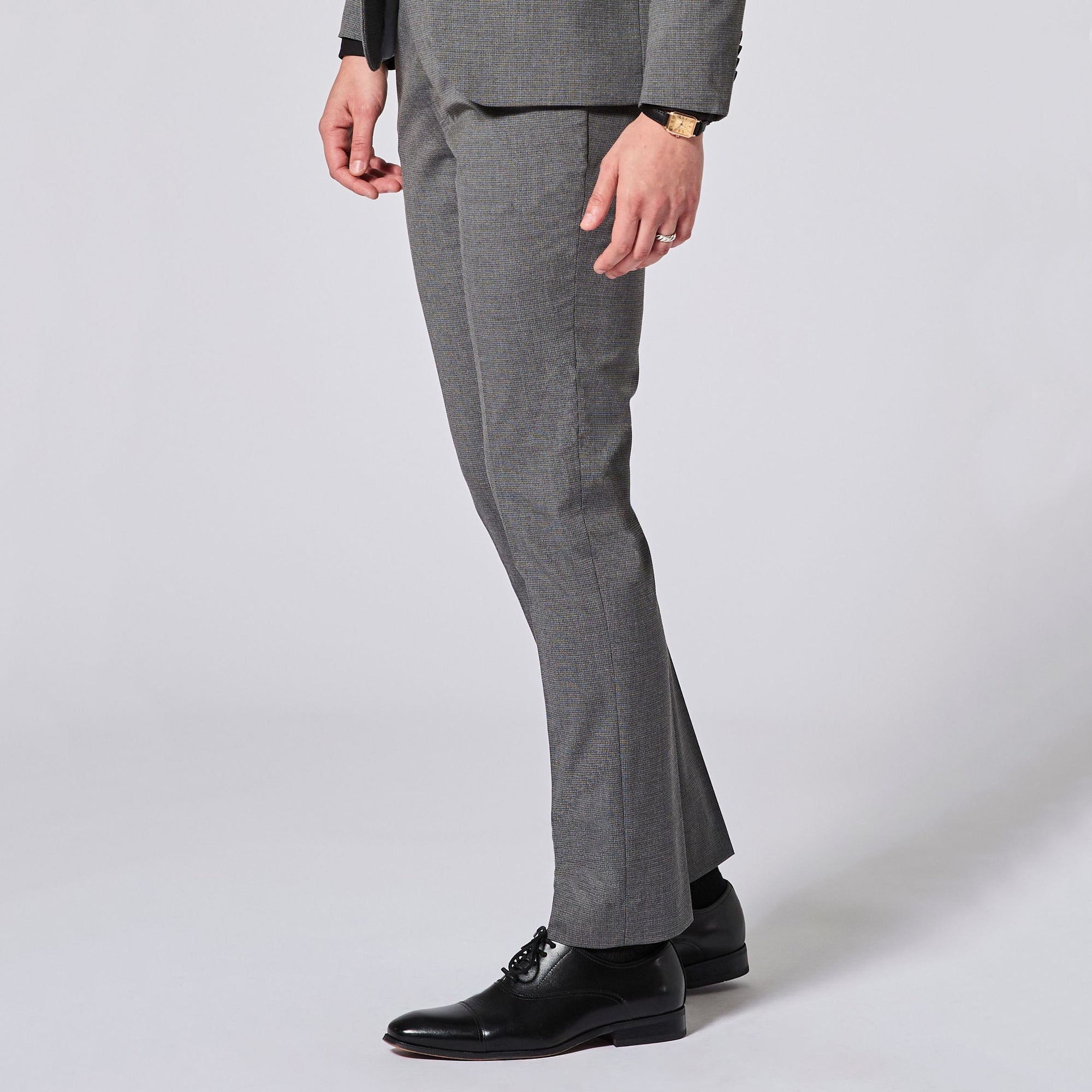Gray suit pants worn by a person on a white background. Color: Gray Lattice