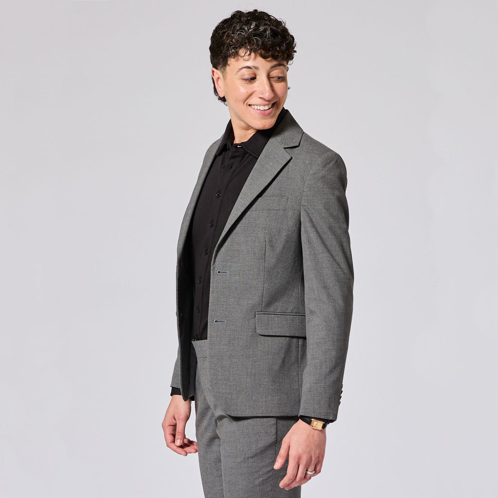 Person wearing a gray suit and black shirt on a light gray background. Color: Gray Lattice