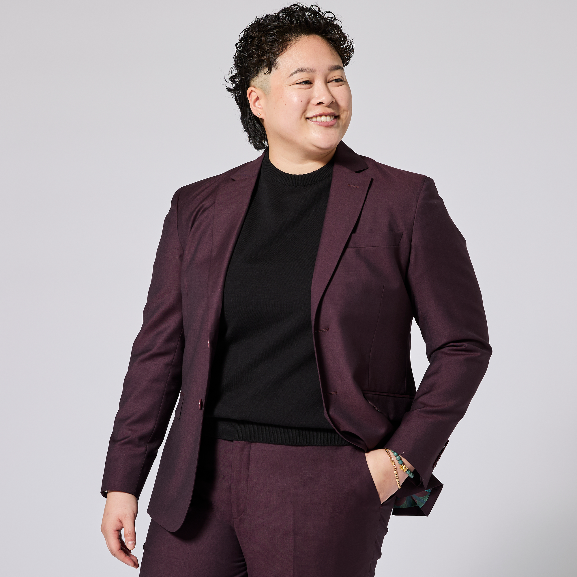Person wearing an Oxblood maroon suit with a black shirt on a light gray background. Color: Deep Oxblood