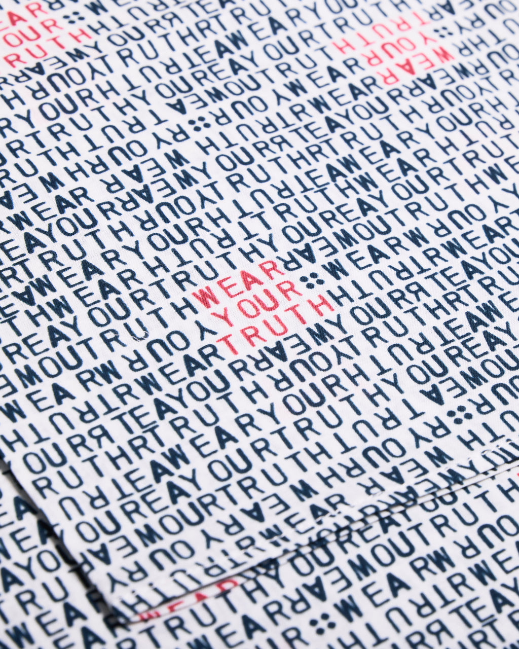 Text pattern with 'WEAR YOUR TRUTH' in red on a white bandana.