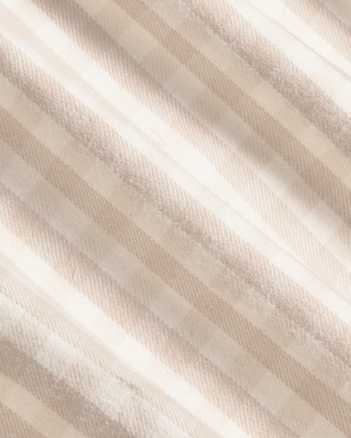 A close-up of a soft, textured fabric with diagonal stripes in warm beige and cream tones. Color: Cream Check Flannel