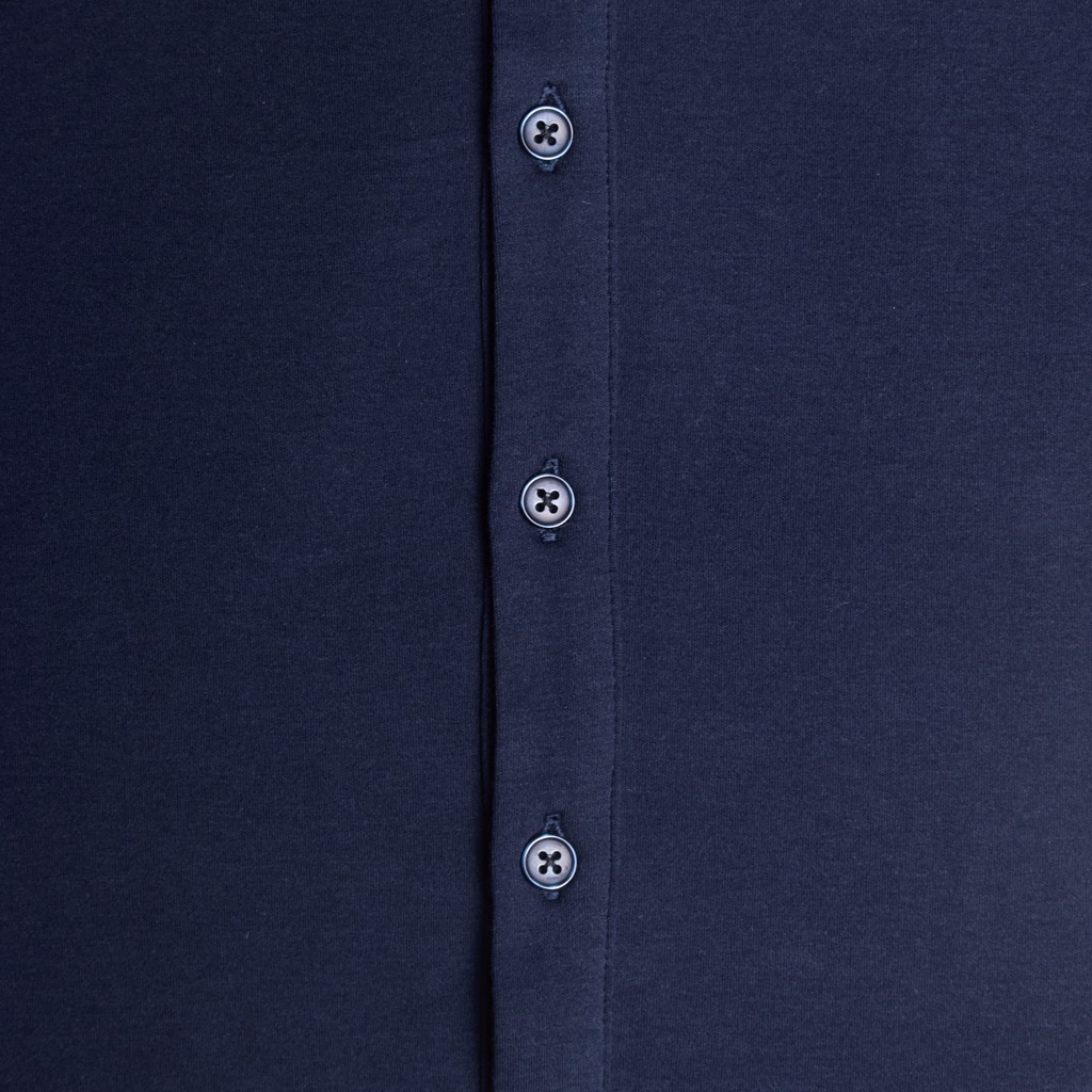 Close-up of a navy shirt with buttons on a plain background. Color: Navy