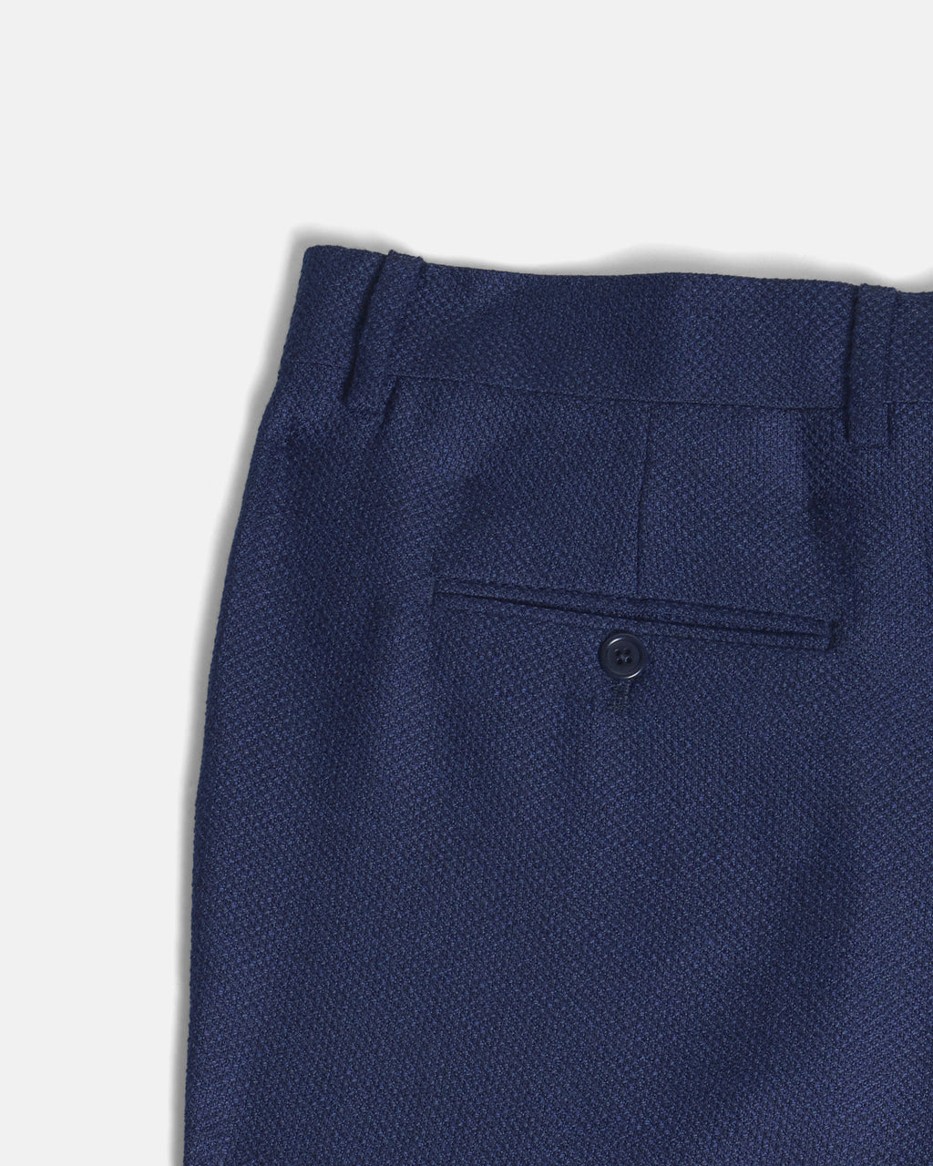 Close-up of a pair of blue textured pants on a light gray background. Color: Navy Textured