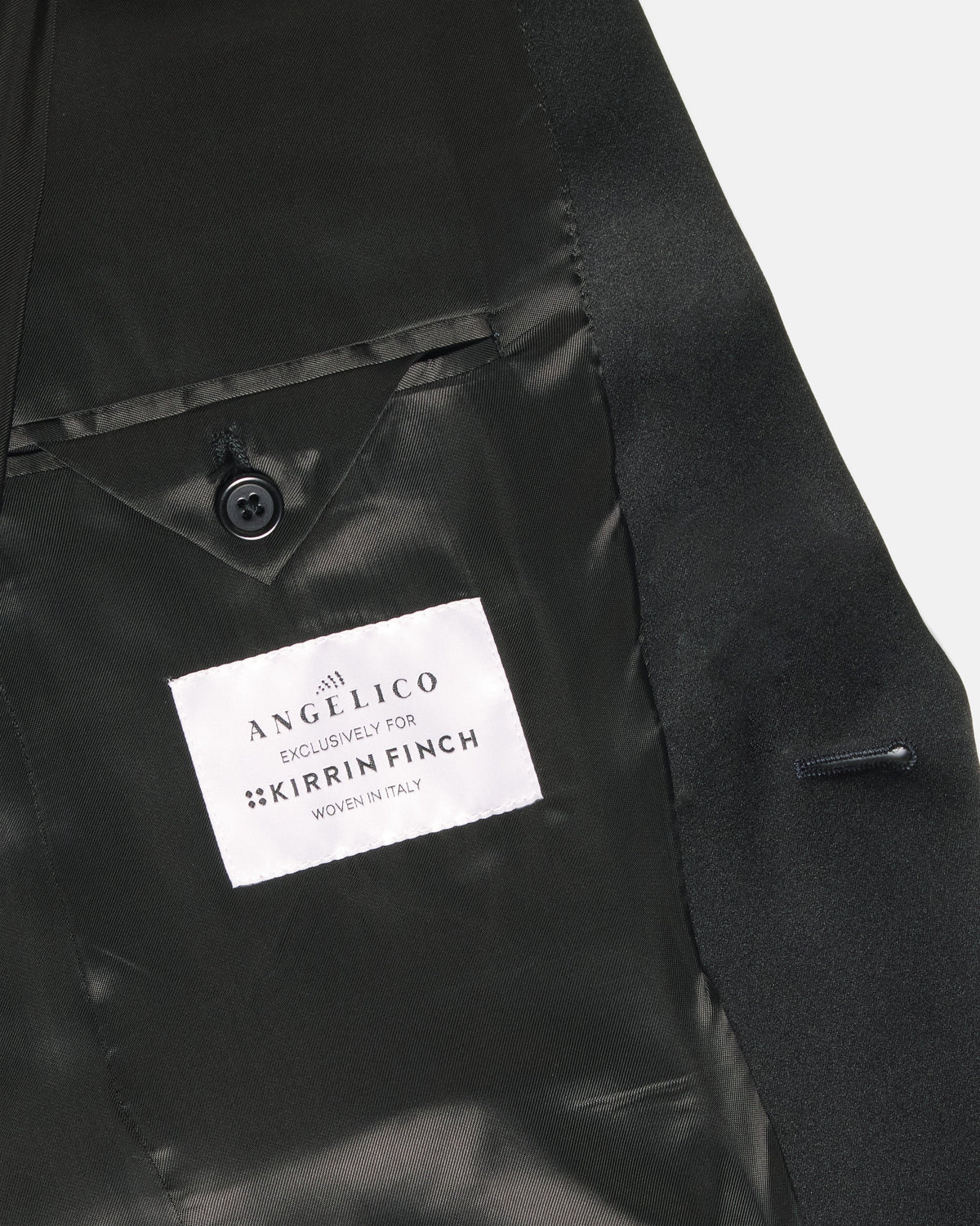 Close-up of a black satin lapel with a white fabric brand label. Color: Gilded Brocade