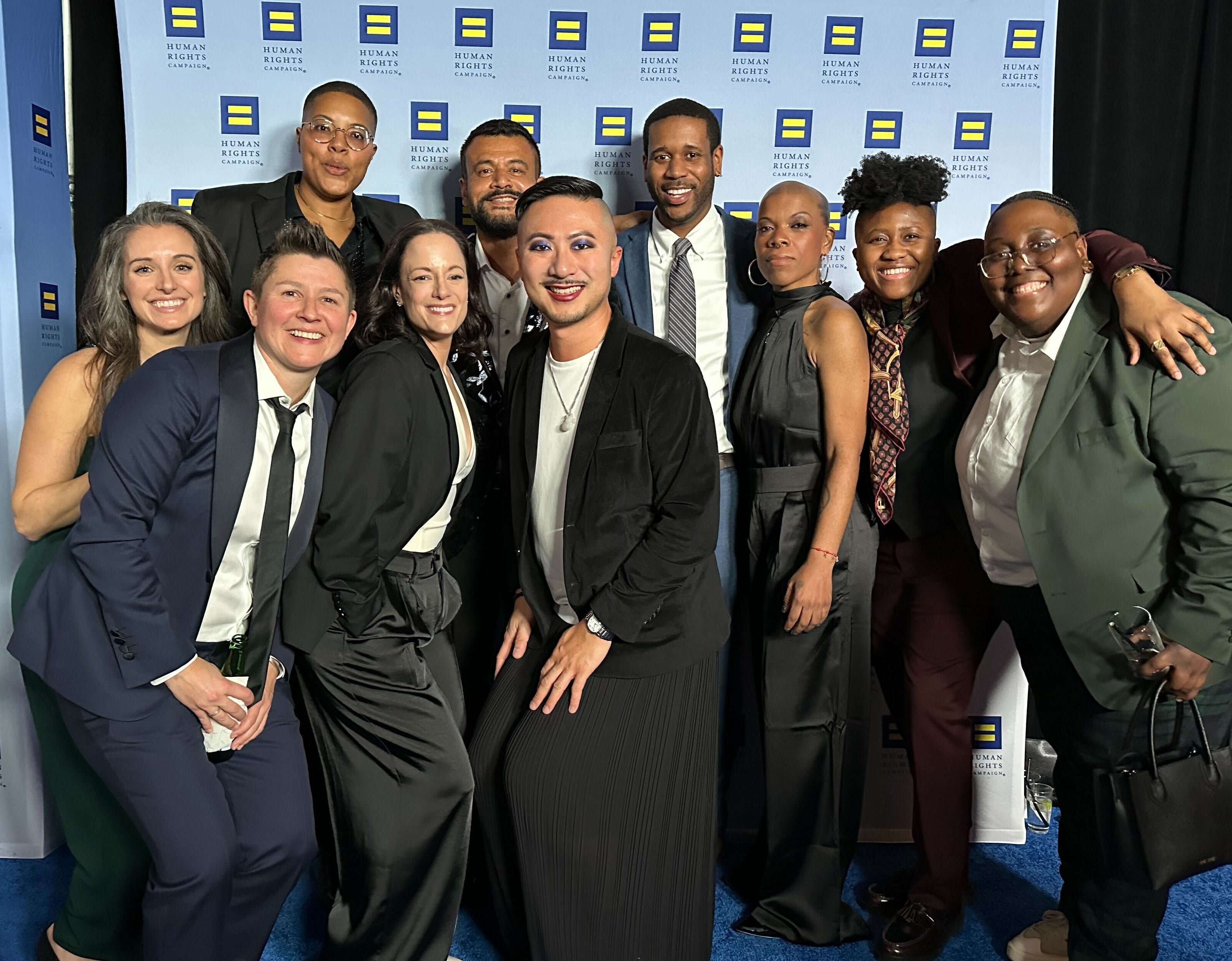 Group of people posing for a photo in front of a backdrop with logos