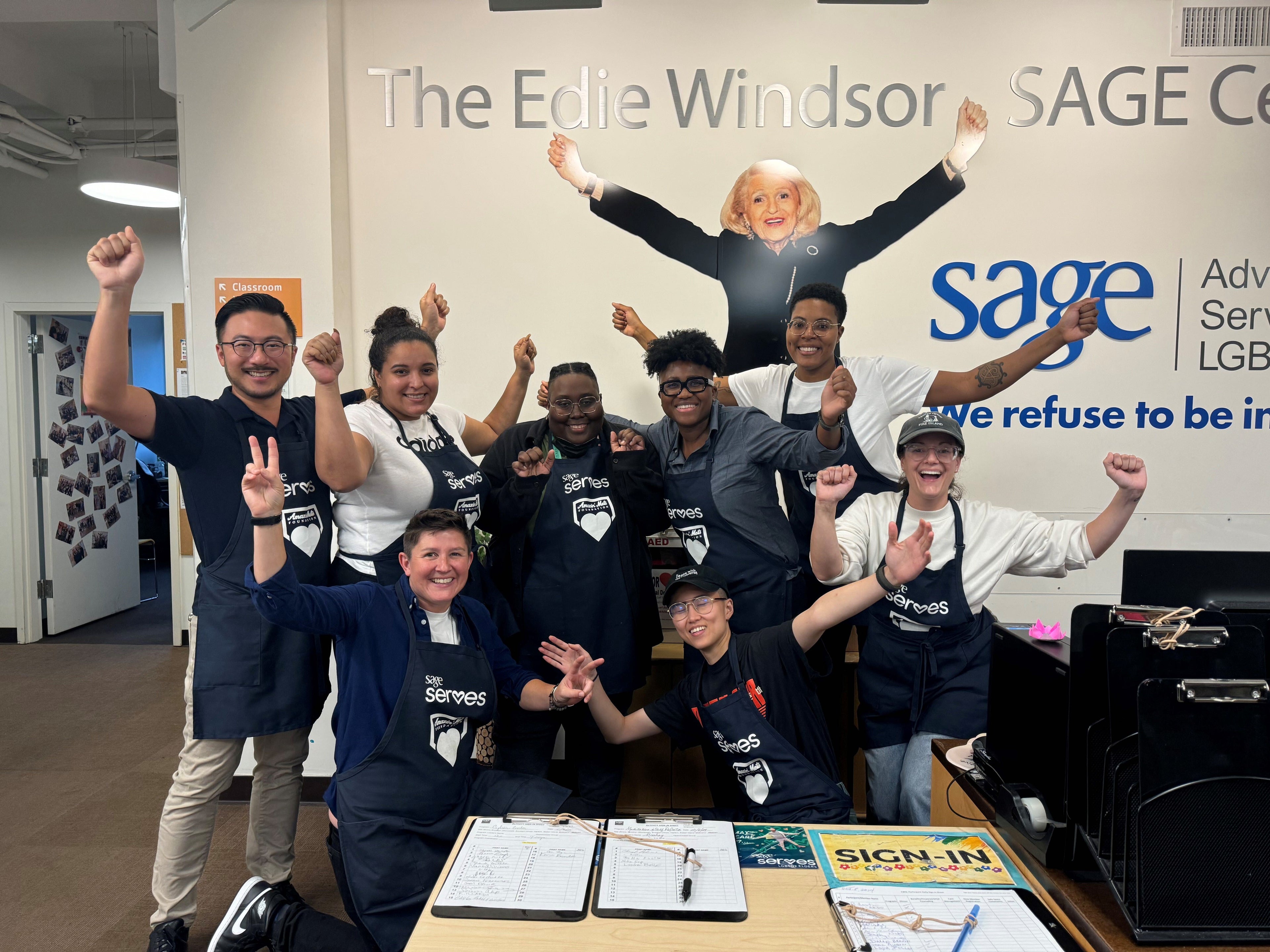 The Kirrn Finch team in matching outfits with raised arms in front of a Sage sign.