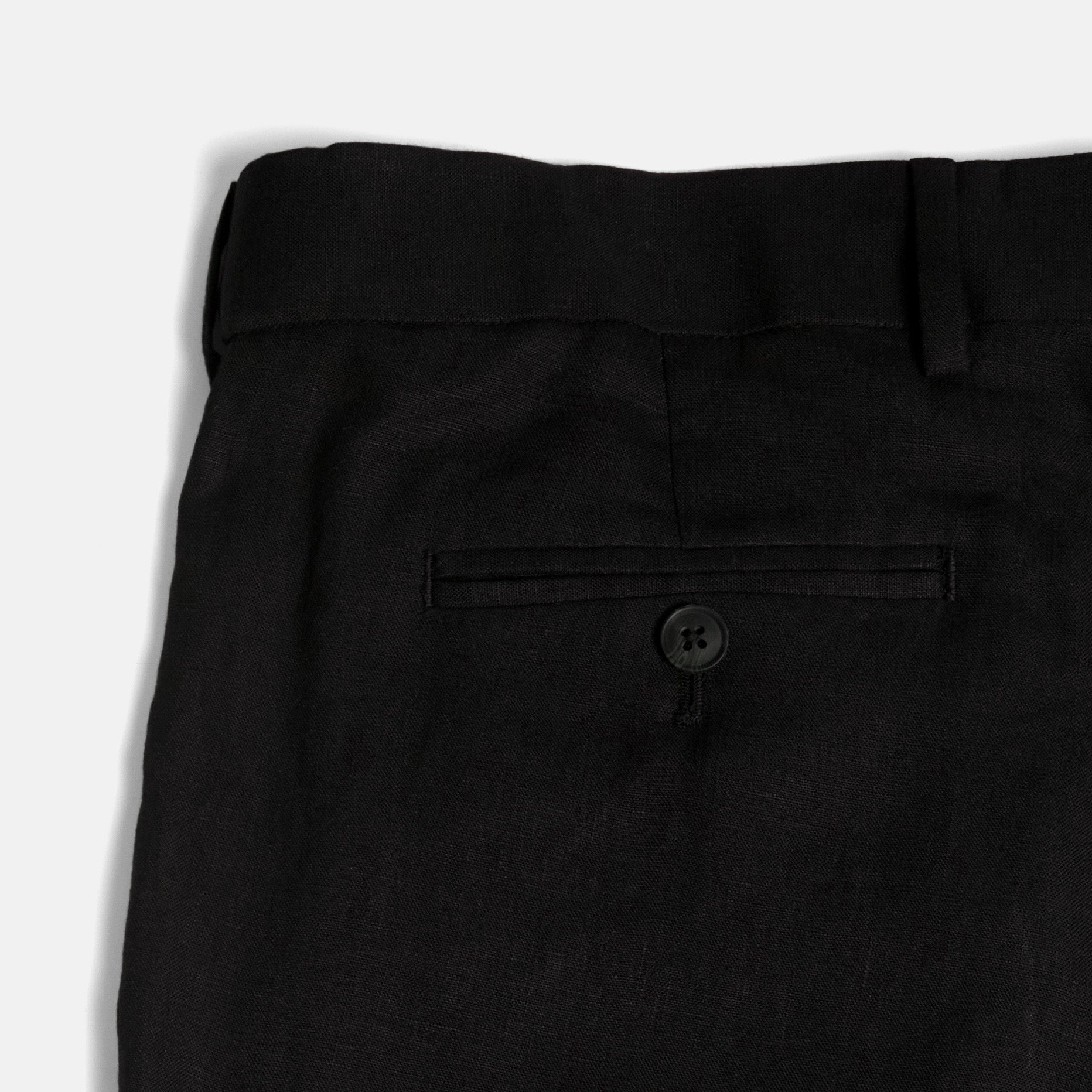 Close-up of black pants with a button on a white background. Color: Black