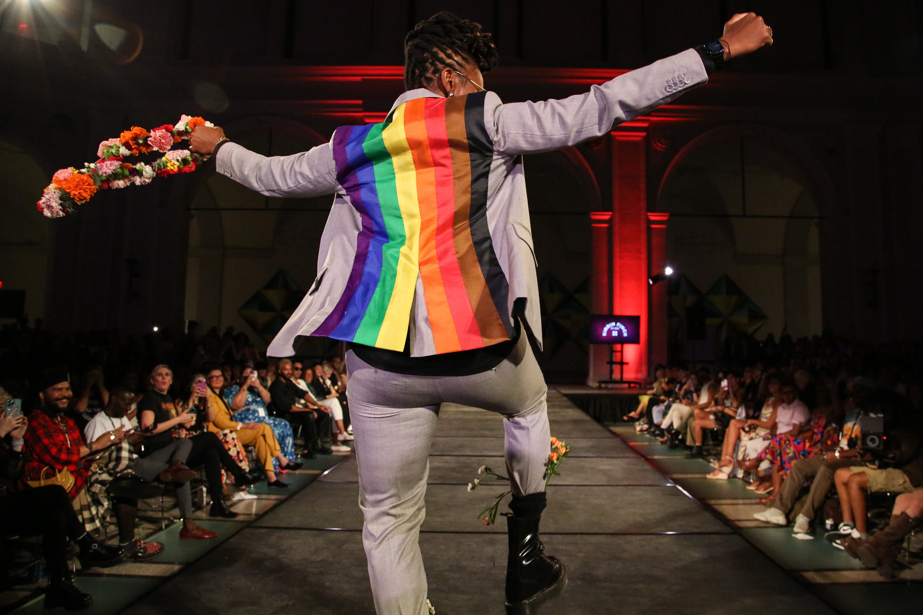Model walking the runway in a custom Kirrin Finch suit featuring a pride flag on the back of the blazer.