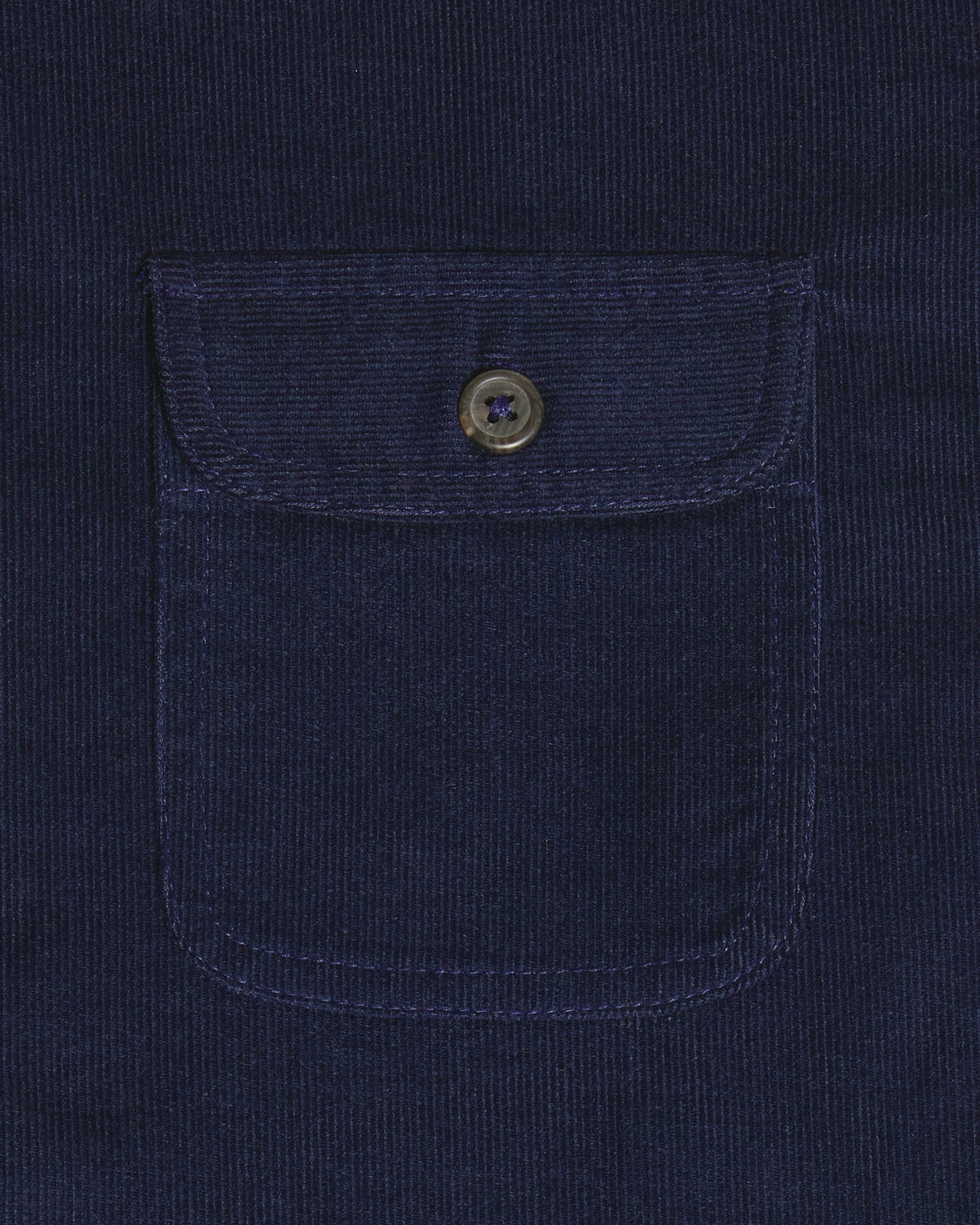 Close-up of a dark navy corduroy pocket with a buttoned flap on a matching navy corduroy garment. Color: Maritime Blue