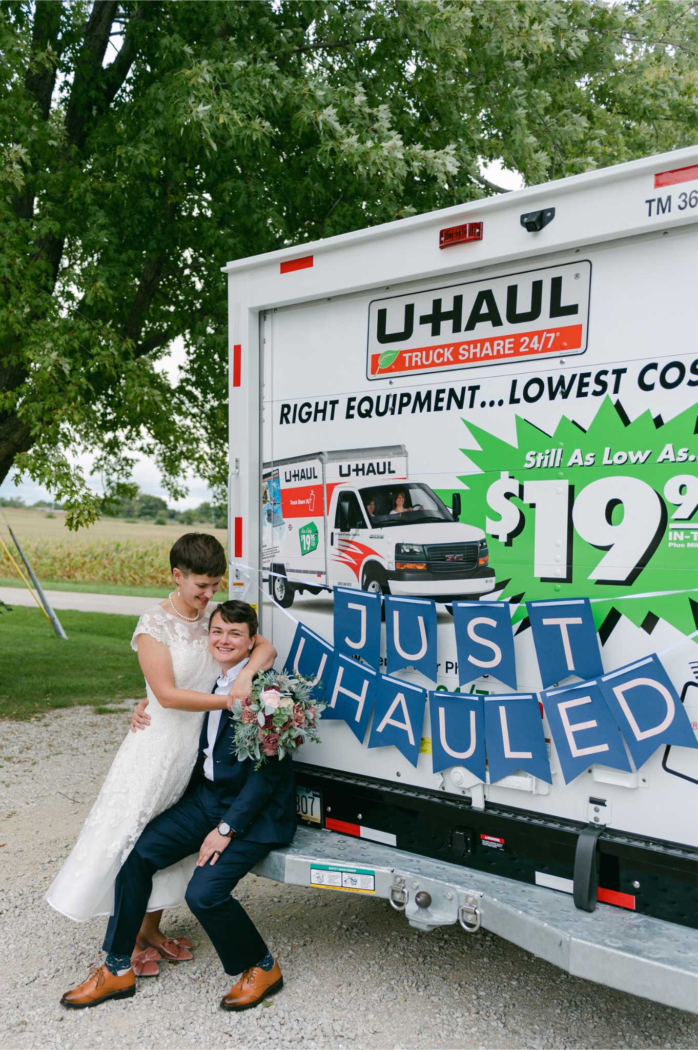 Newlyweds Meg and Abigail posing at the back of a U-Haul truck