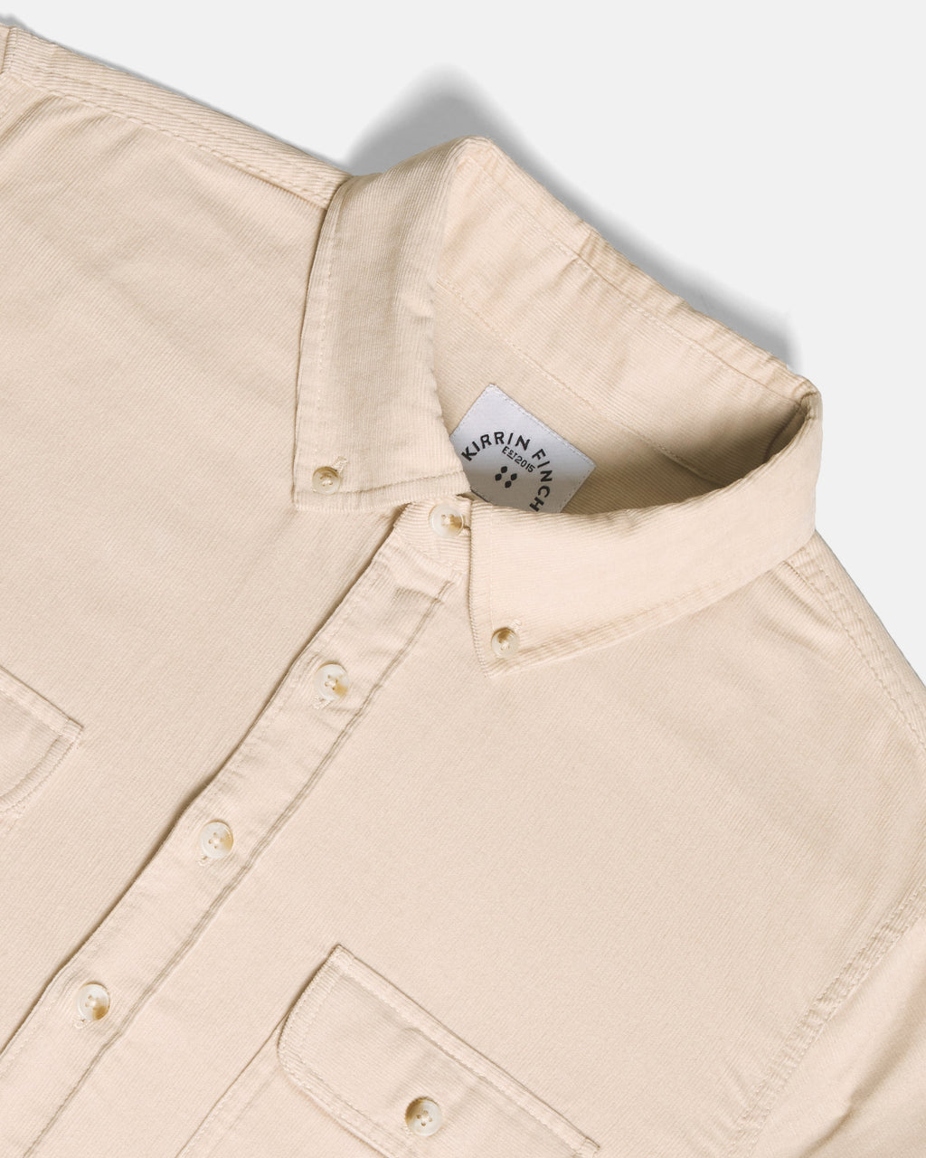 Close-up of a light beige button-down shirt collar, set against a clean off-white background.  Color: Oatmeal