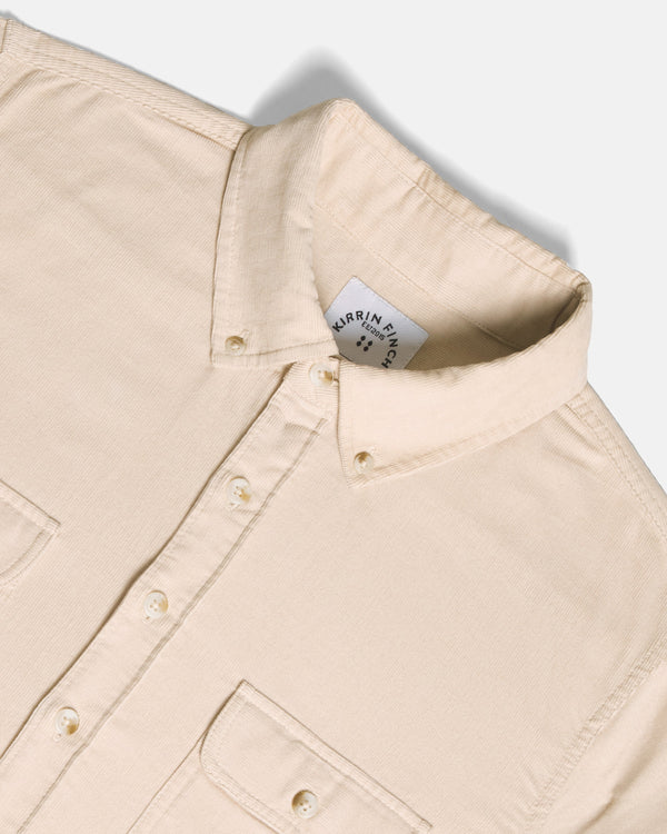 Close-up of a light beige button-down shirt collar, set against a clean off-white background.  Color: Oatmeal