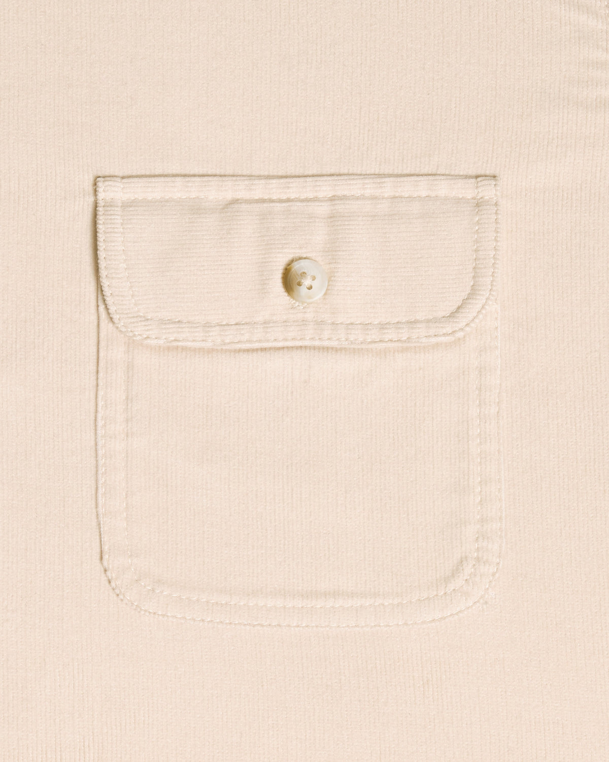 Close-up of a cream-colored textured fabric with a single buttoned flap pocket.  Color: Oatmeal