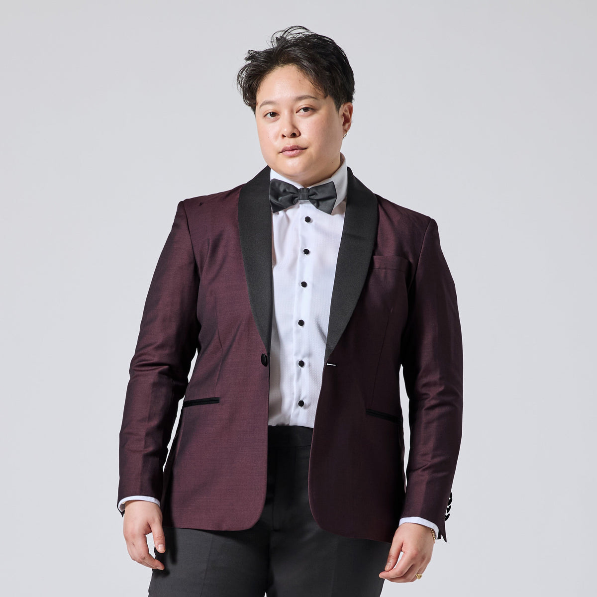 Model wearing a Deep burgundy tuxedo blazer over a white shirt with black buttons and a matching bow tie. Color: Deep Oxblood