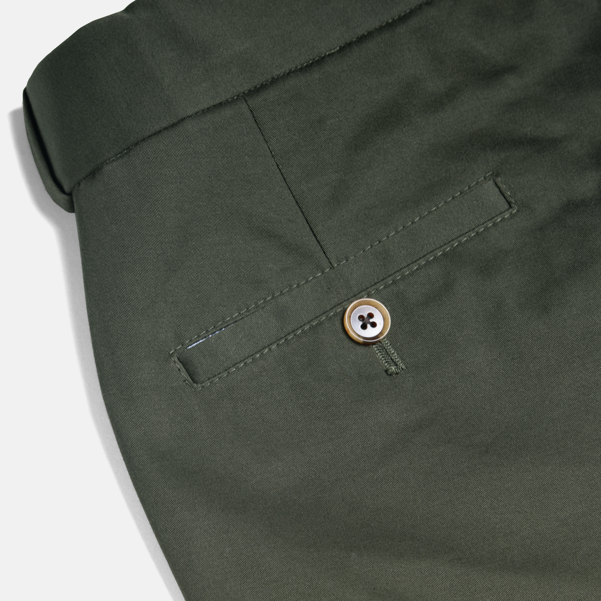Close-up of olive chinos showcasing back pocket button. Color: Olive