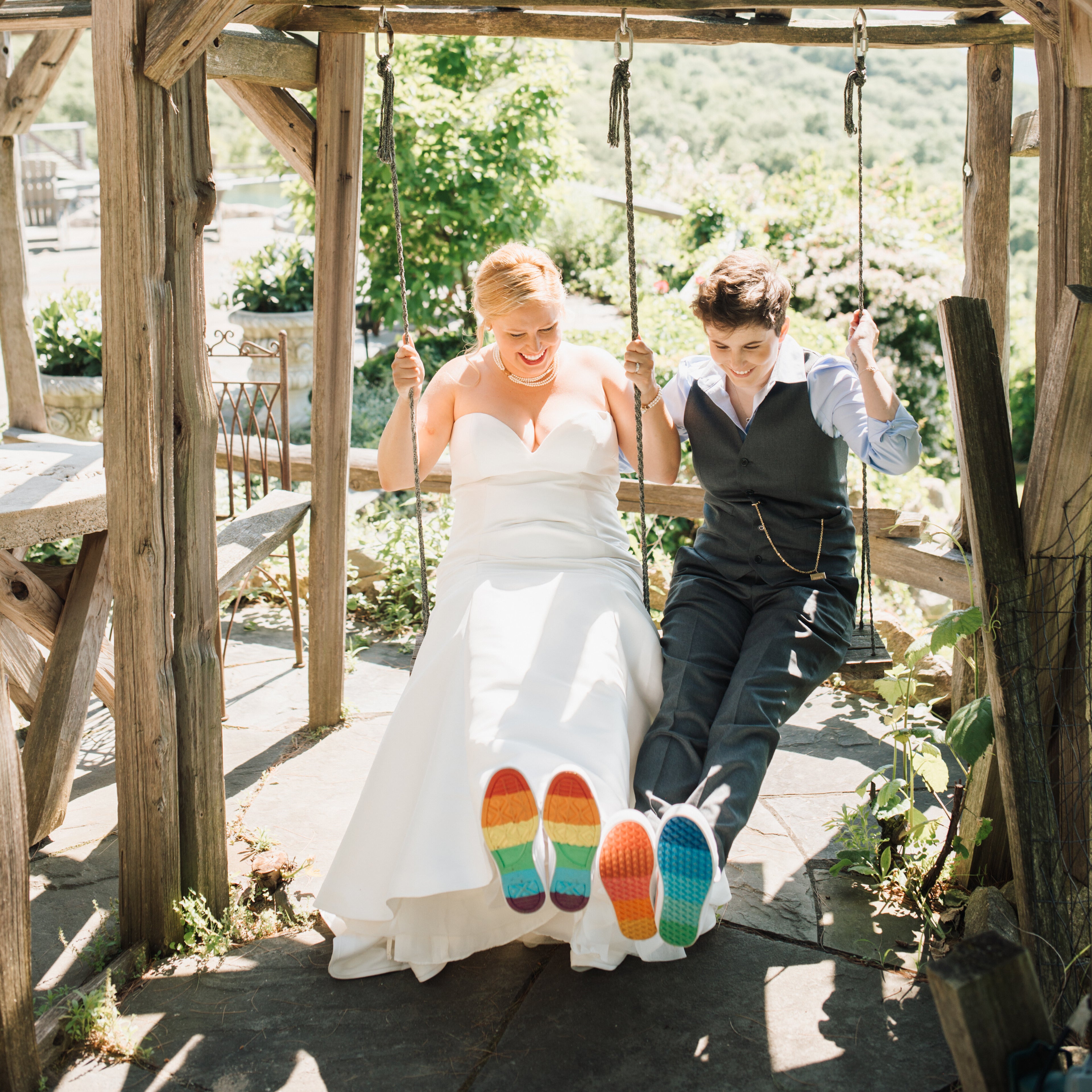 Jules and Michelle sitting on a swing showing rainbow colored shoe soles 