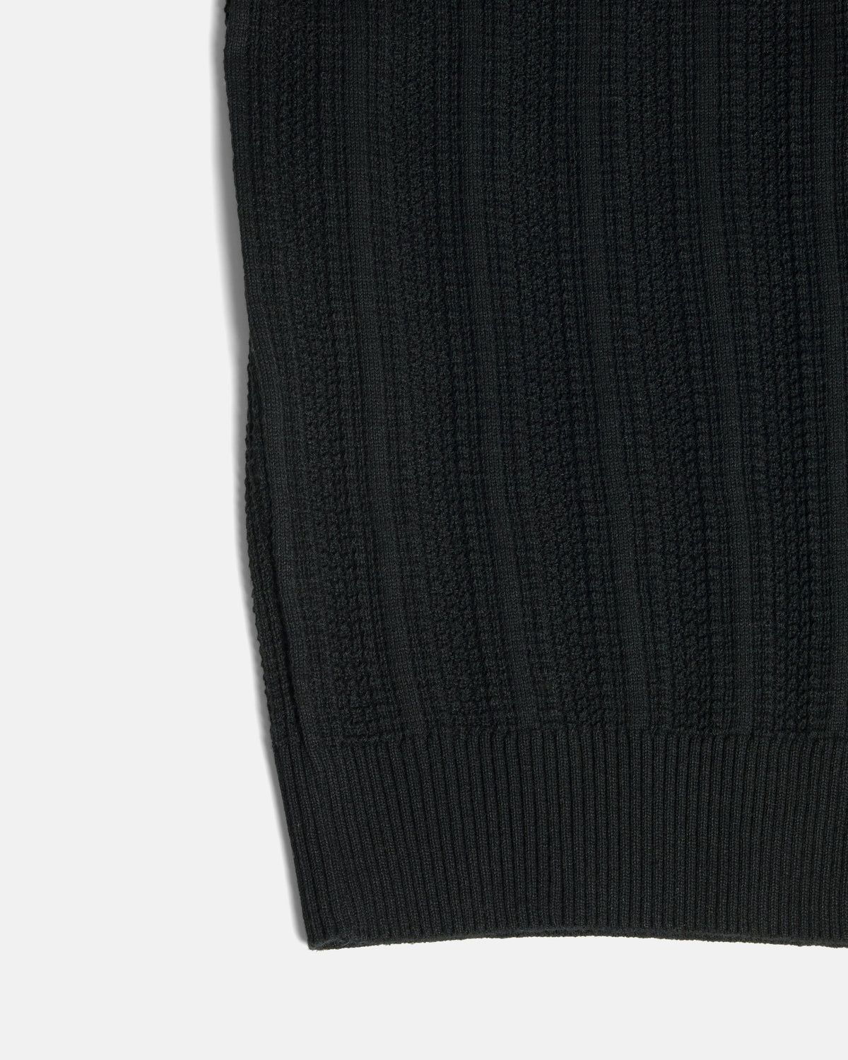 Close-up of a black ribbed knit fabric, showing the texture and cuff detail against a plain white background. Color: Black