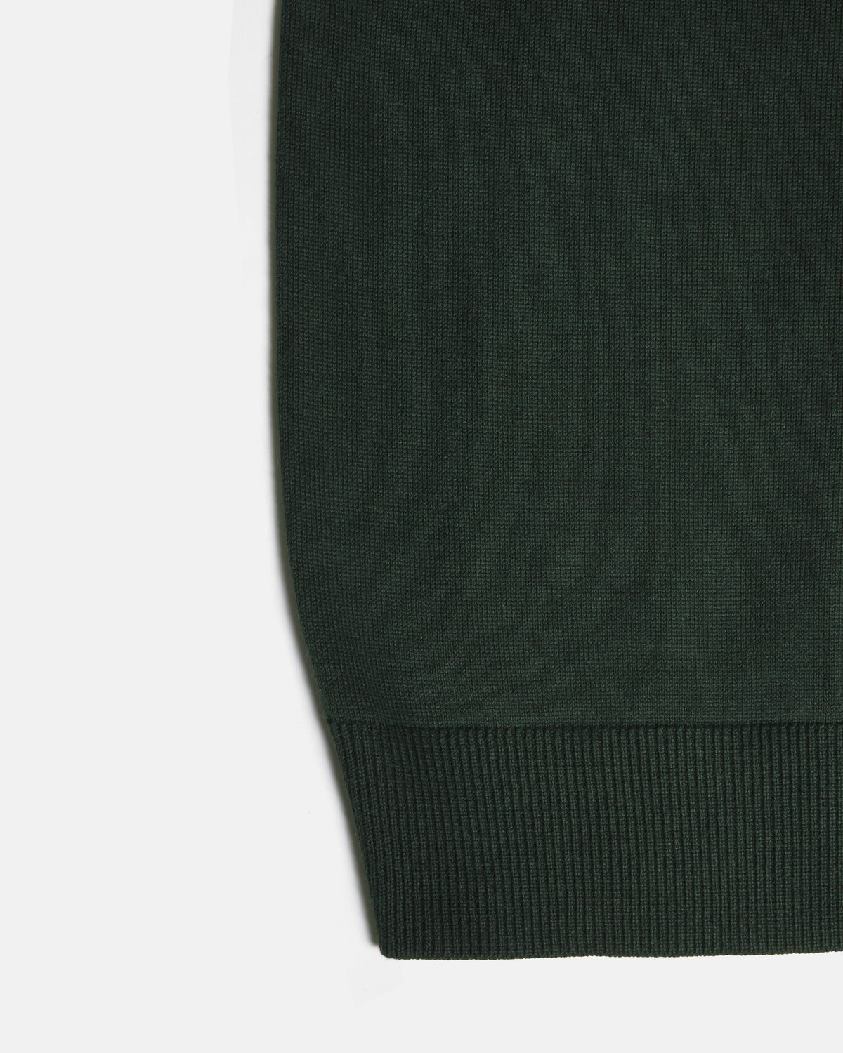 Close-up of a dark forest green knit fabric with a ribbed cuff on a white background. Color: Evergreen