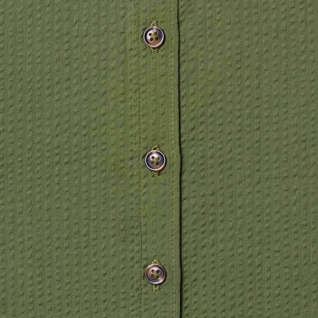 Close-up of a green textured shirt with buttons. Color: Nopales