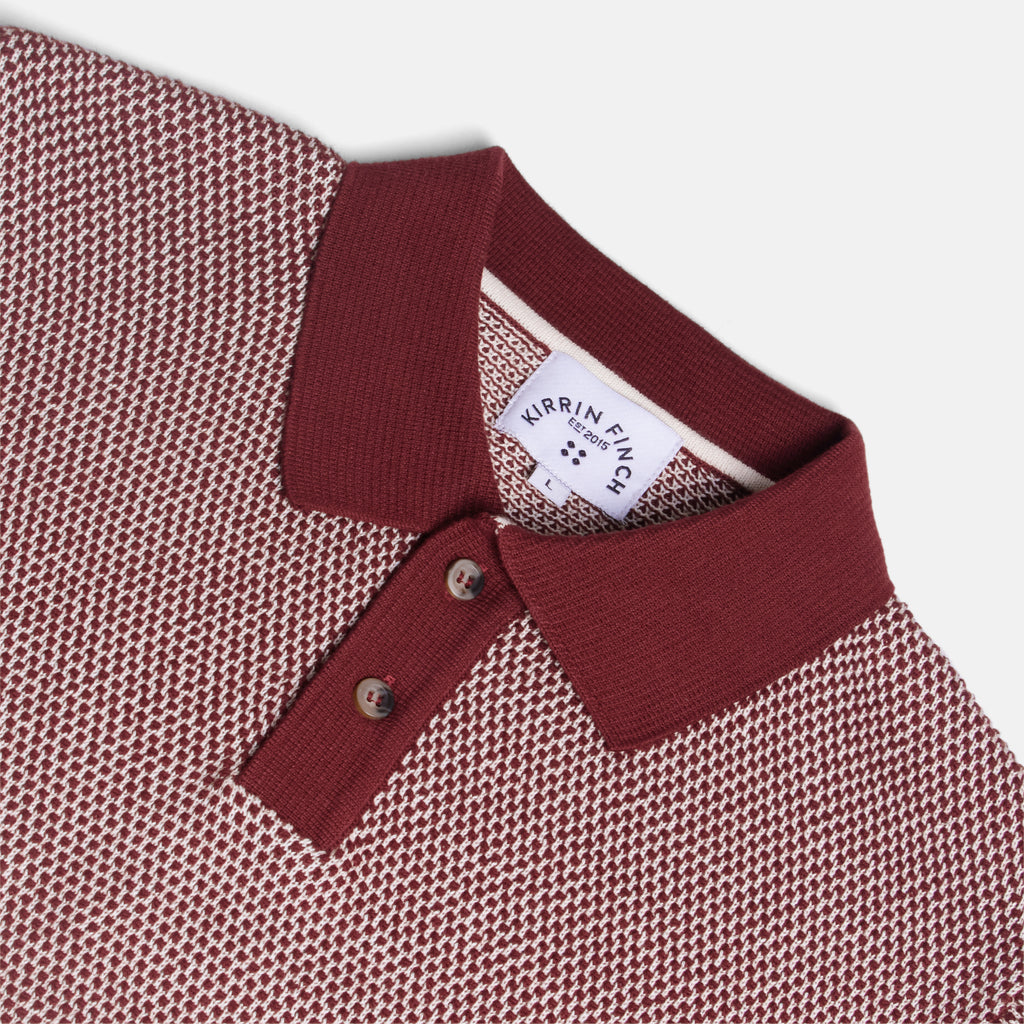 Close-up of a knit polo shirt collar and upper chest in a burgundy and cream micro-pattern. Color: Auburn