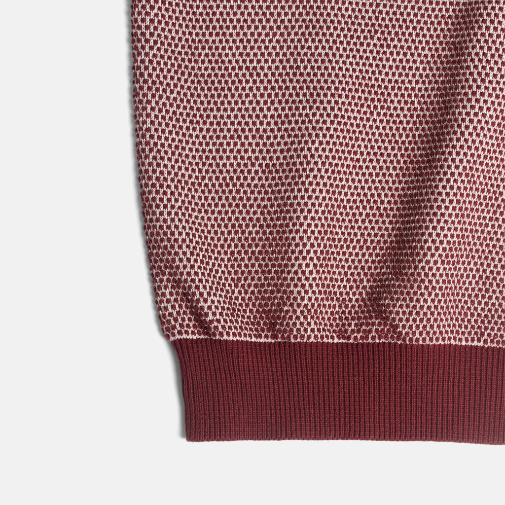 Close-up detail of a ribbed knit garment corner showing a dusty rose mesh body and a darker burgundy ribbed cuff on a light gray background. Color: Auburn