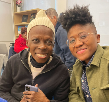 Two people sitting together in a casual setting, one holding a phone.