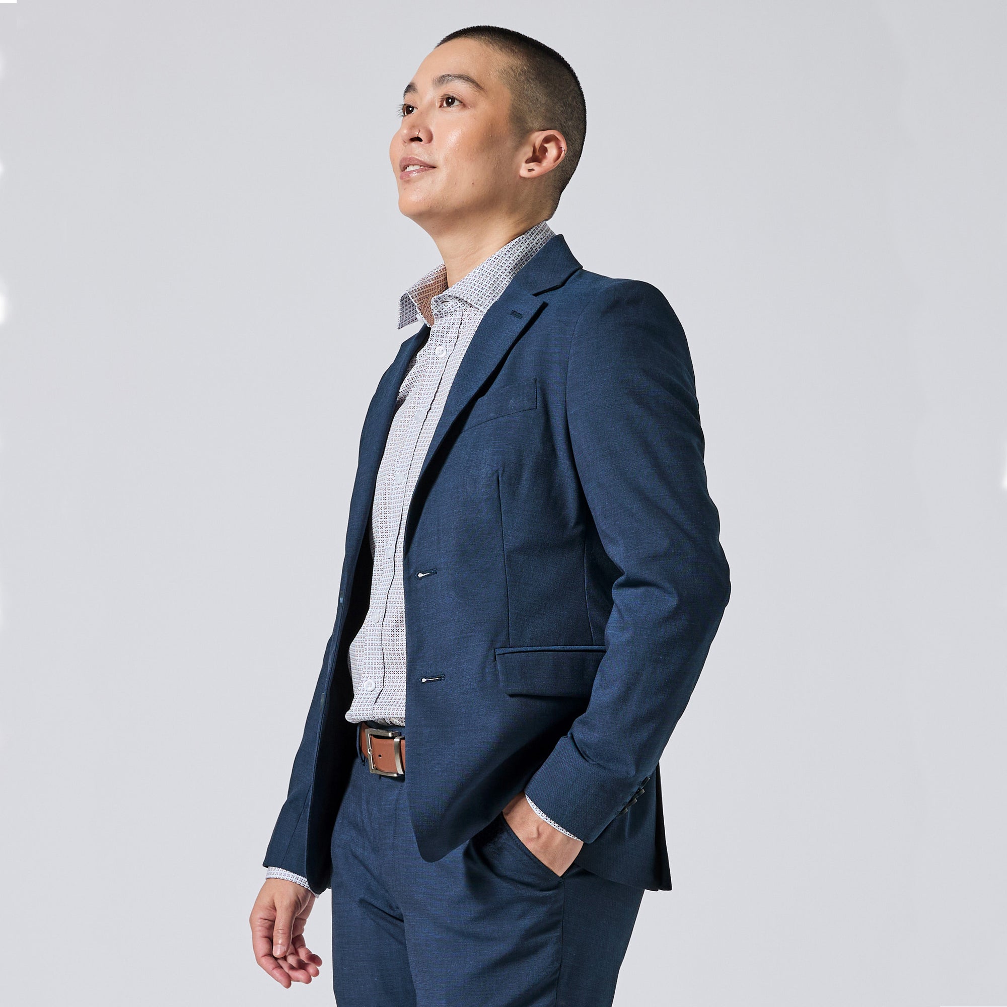 Person wearing an Atlantic blue suit jacket and matching trousers, styled with a light blue and white checkered dress shirt, standing against a solid light gray background. Color: Atlantic Blue