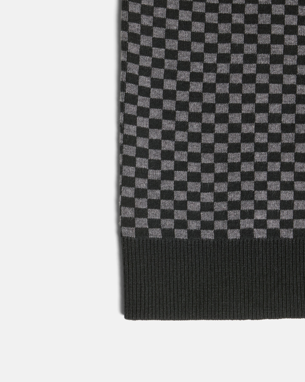 Close-up of a black and gray checkerboard knit fabric with a ribbed black border, shown on a light gray background. Color: Shadow Checker