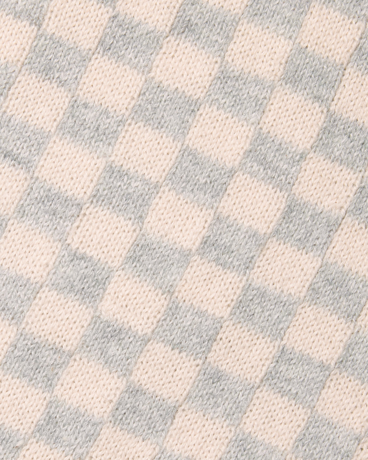 A close-up of a knit fabric with a soft checkerboard pattern in pale blush pink and light gray. Color: Saltstone Checker