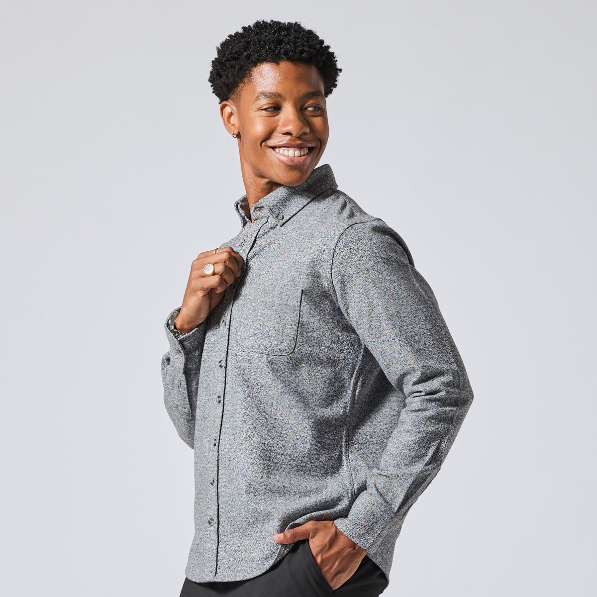 Smiling model wearing a textured gray long-sleeve button-down shirt, posing against a light gray studio background. Color: Static Flannel