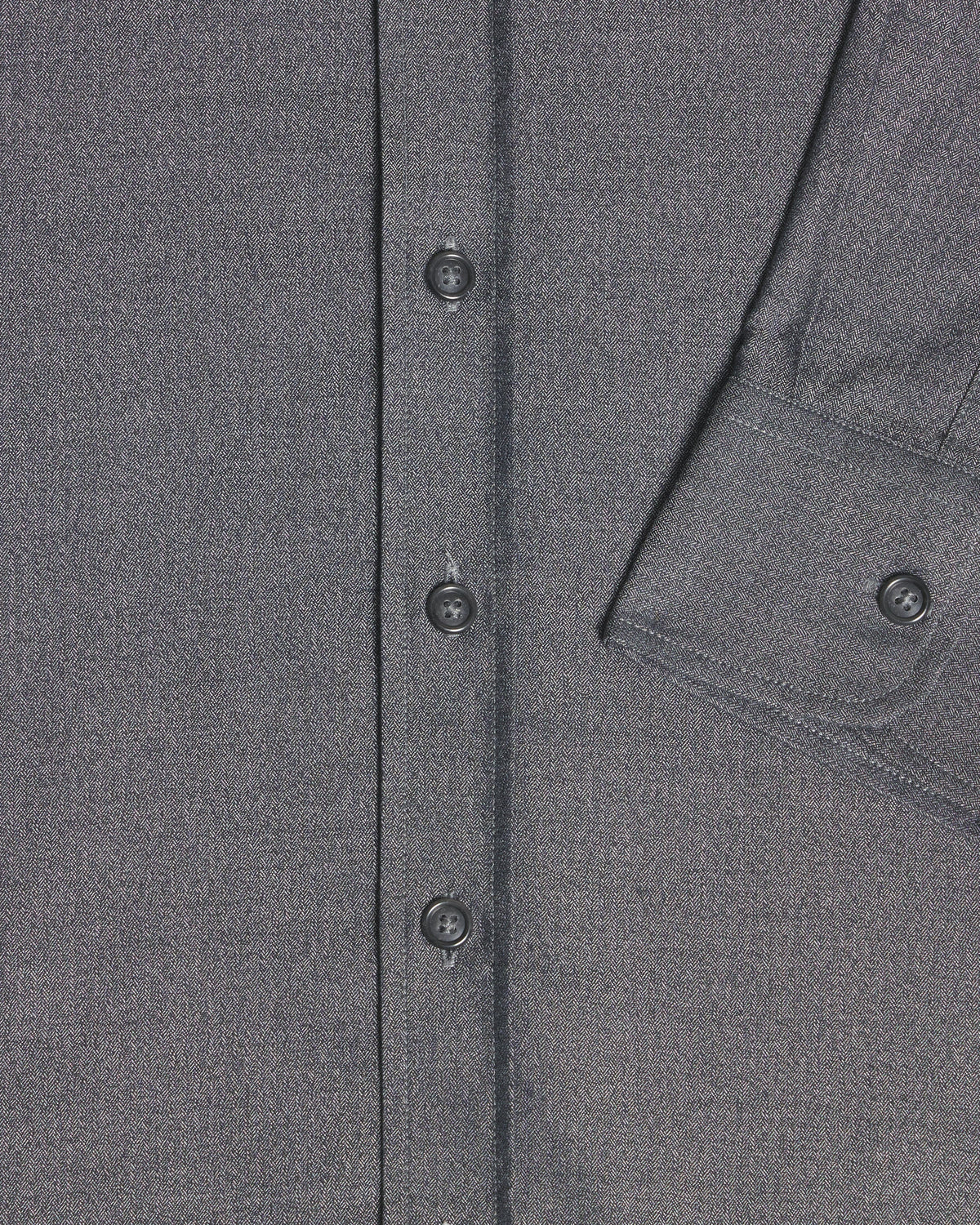 Close-up of a dark gray textured fabric garment showing the button placket and a partial chest pocket with a buttoned cuff. Color: Steel Marl Herringbone