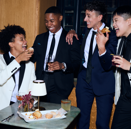 Group of four people eating drinking and laughing in formal wear