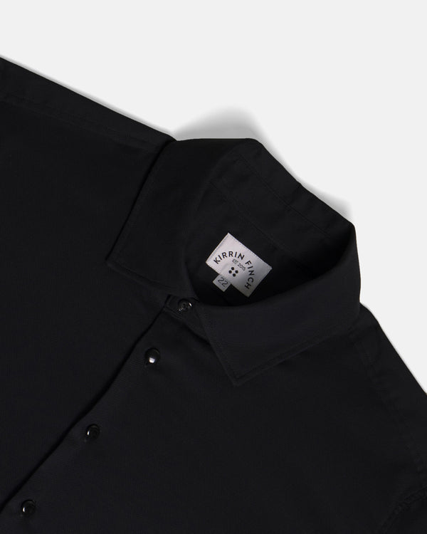 Close-up of a black collared button-up shirt. Color: Black