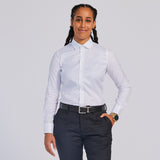 A person wearing a white easy-care dress shirt with a spread collar, white buttons, and long sleeves, paired with dark trousers and a belt. Color: White