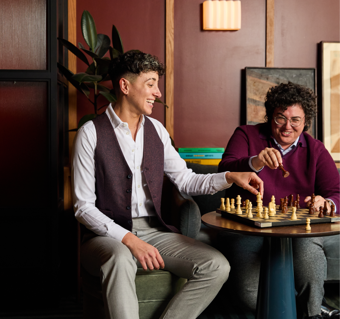 Two people playing chess in a cozy indoor setting with warm lighting.