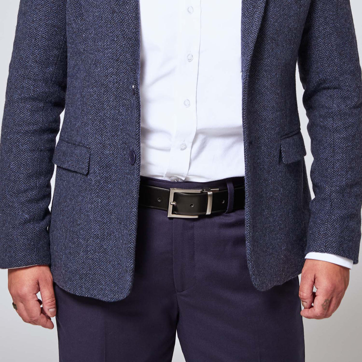 Black leather belt with zinc belt buckle on model wearing Georgie navy blue pants and navy blue tweed blazer. Color: Black/Brown