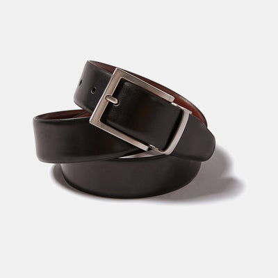 Reversible leather belt by Kirrin Finch coiled upon itself. Showing Black leather side and zinc belt buckle. Color: Black/Brown